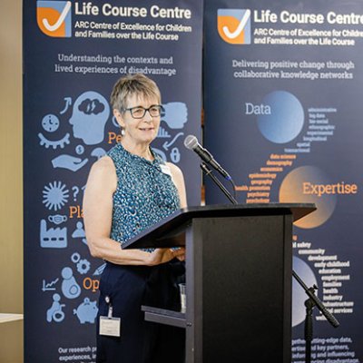 Professor Janeen Baxter standing smiling at a podium